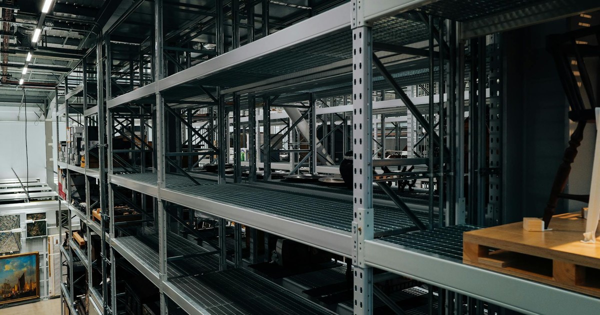 Empty metal storage racks in a spacious industrial warehouse setting.