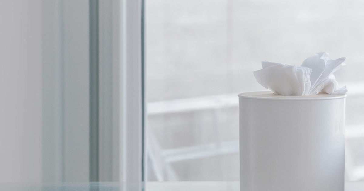 Elegant white tissue container on glass surface, evoking simplicity and minimalism.