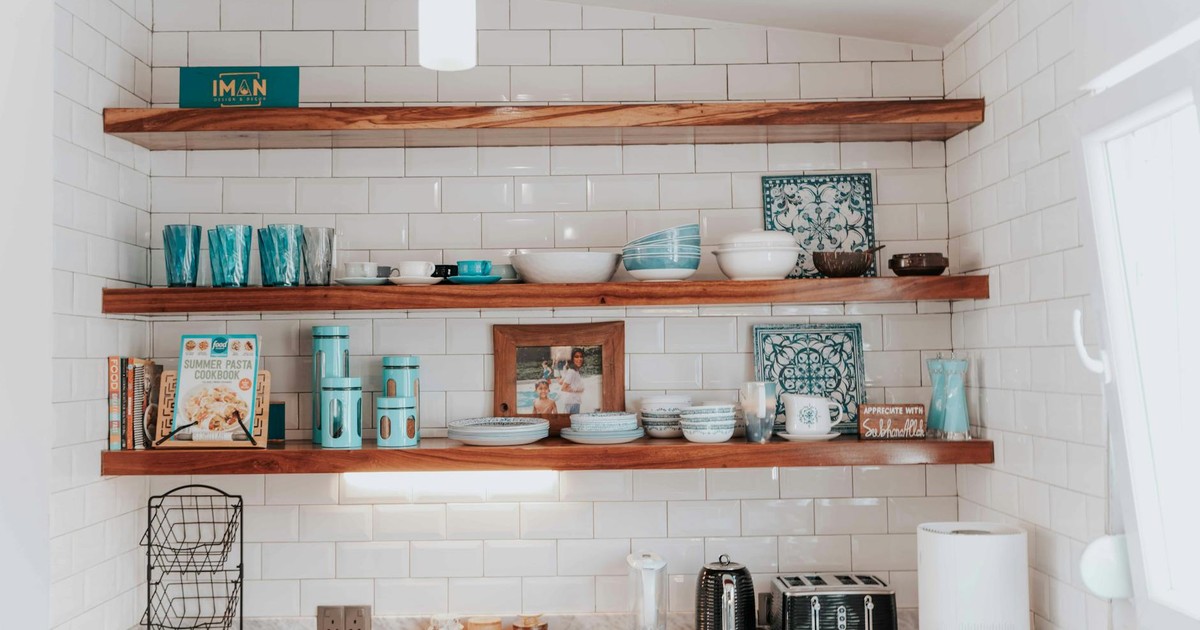 Stylish kitchen with open wooden shelves displaying tableware and decor.