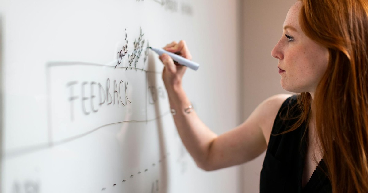 Focused woman writing on a whiteboard during a business planning session.