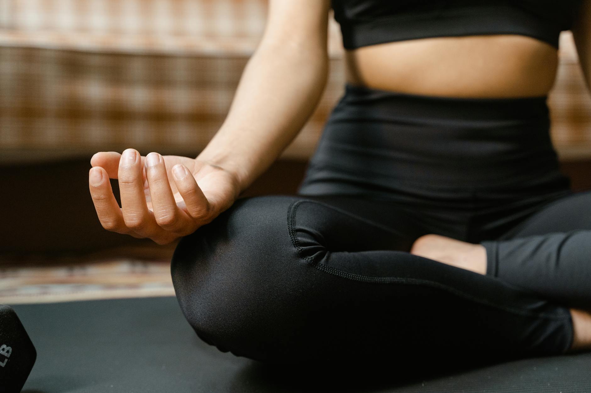 Close-up of a woman meditating in a yoga pose indoors, promoting mindfulness.