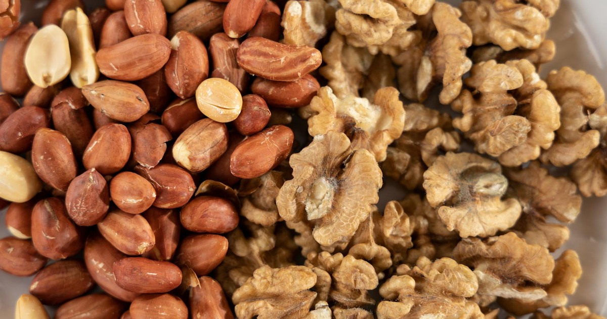 A detailed view of a healthy mix of raw peanuts and walnuts, highlighting texture and variety.