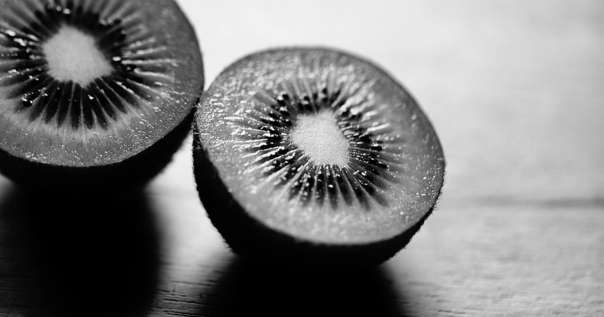 Artistic black and white close-up of two kiwi fruit halves, showcasing detailed texture.
