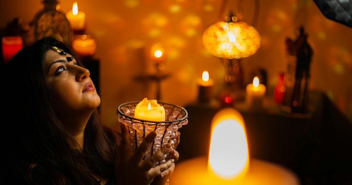 A woman holding a glowing candle in a mystical setting, engulfed in candlelight and spirituality.