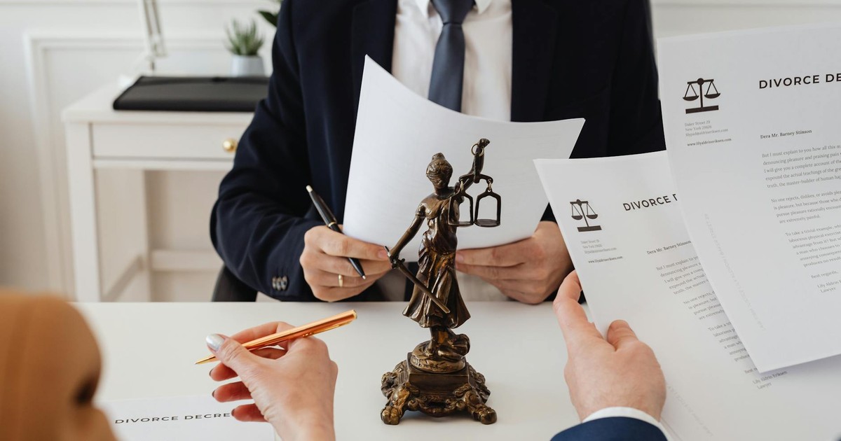 Legal professionals reviewing divorce documents in a law office with a Lady Justice statue.
