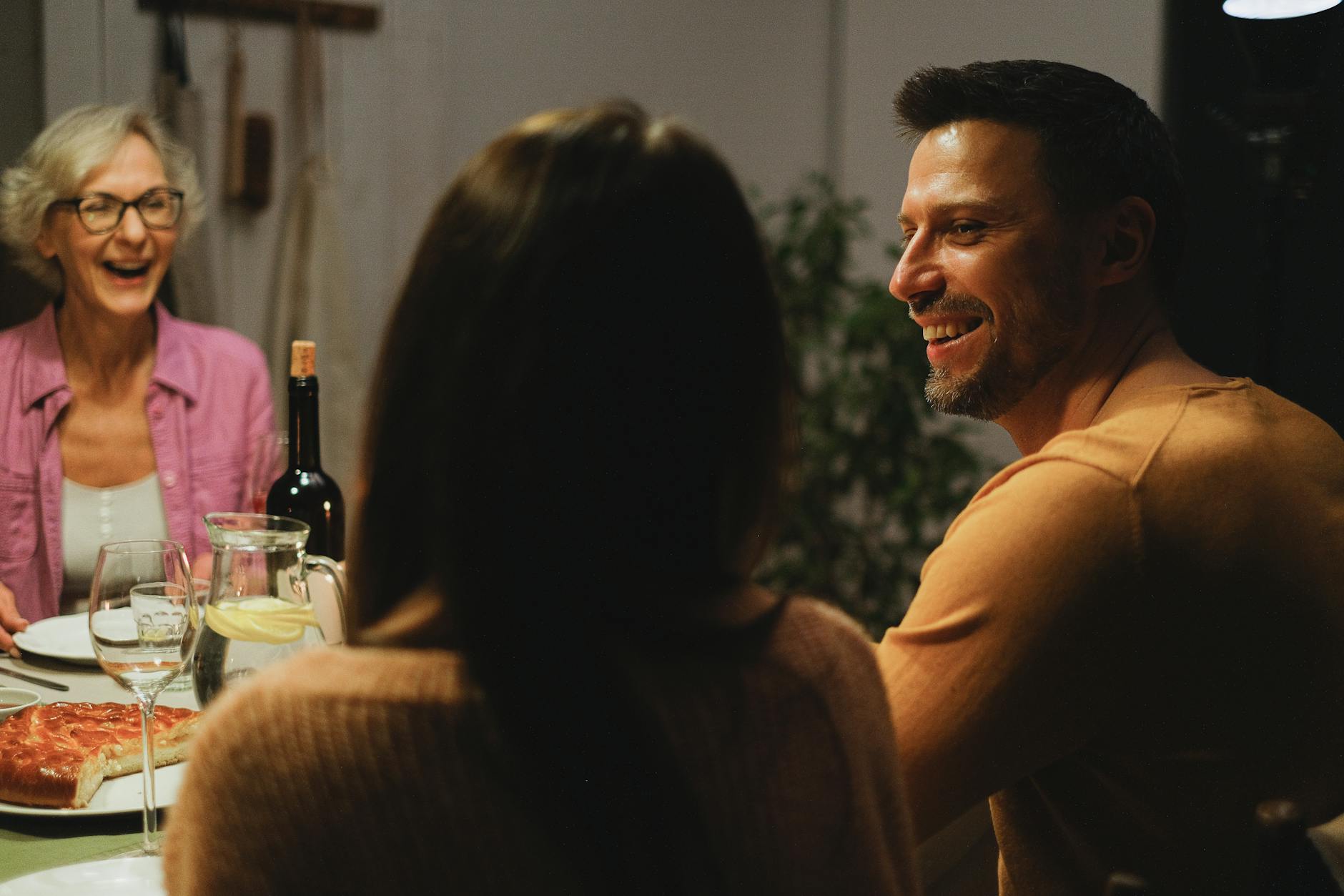A joyful family sharing a dinner and engaging in warm conversation indoors.