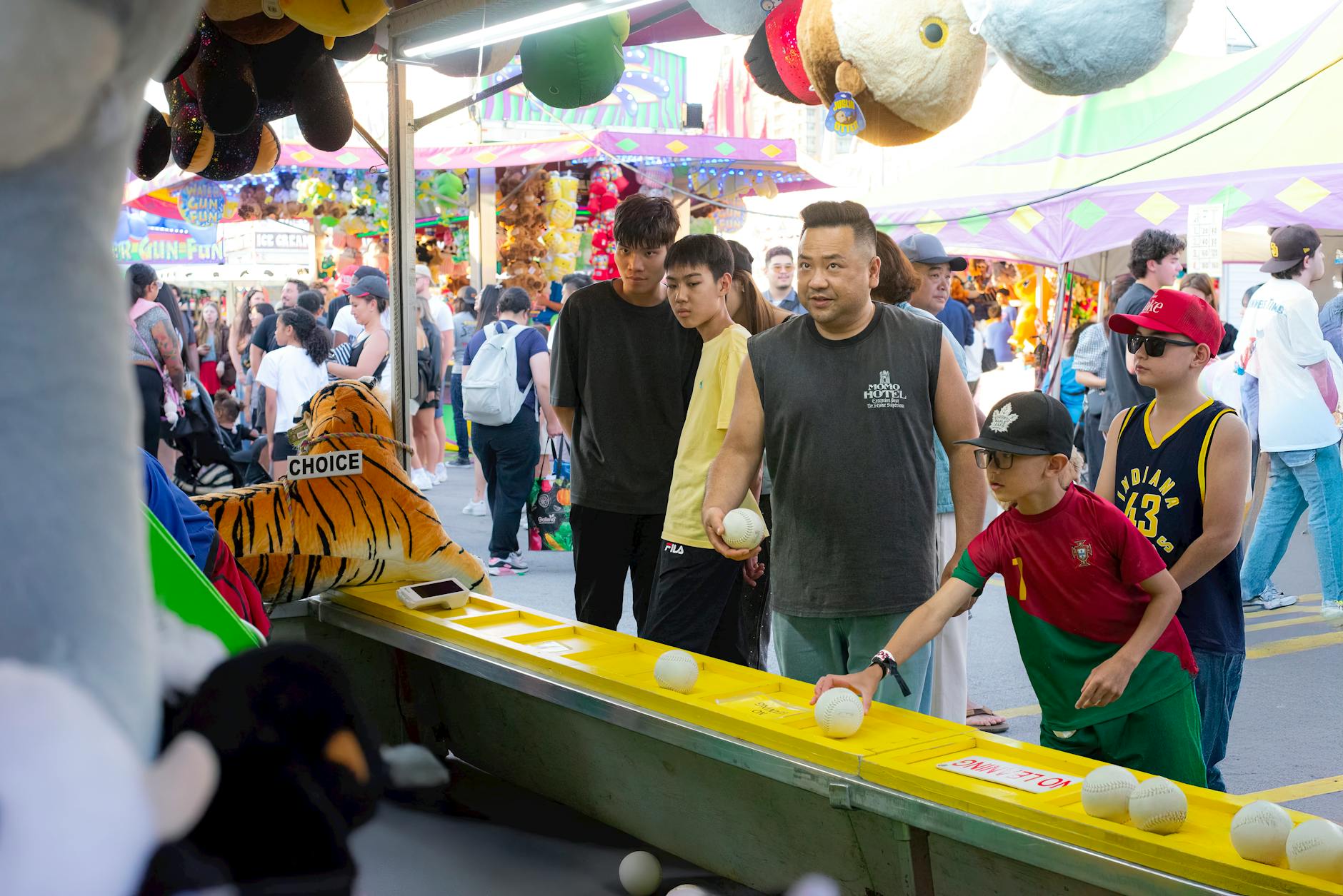 A diverse group of people engages in a fun carnival game, surrounded by vibrant festival activities.