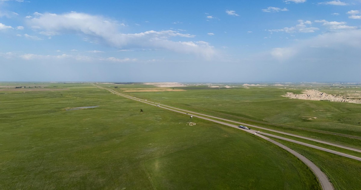 Breathtaking aerial view of vast grasslands spreading under a clear blue sky, highlighting natural beauty.