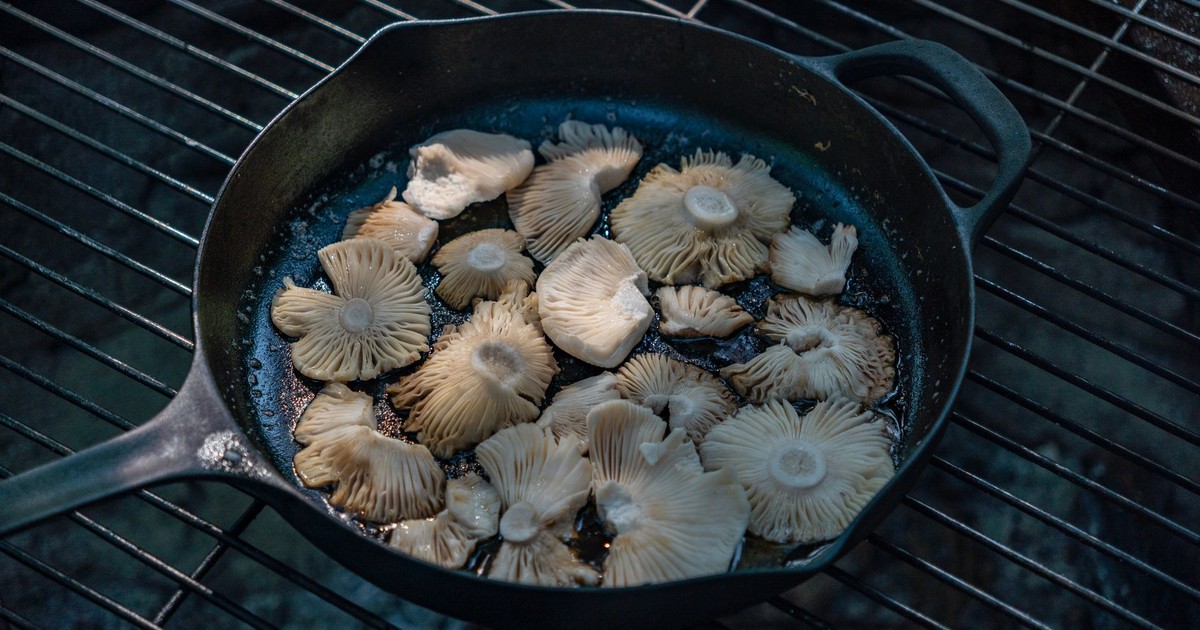 Fresh mushrooms cooking on a black skillet, enhancing the grilled cuisine experience.