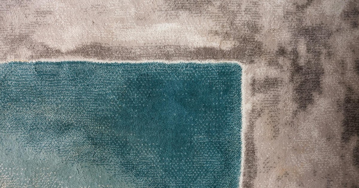 Close-up of a textured carpet showcasing a teal square amidst gray tones.