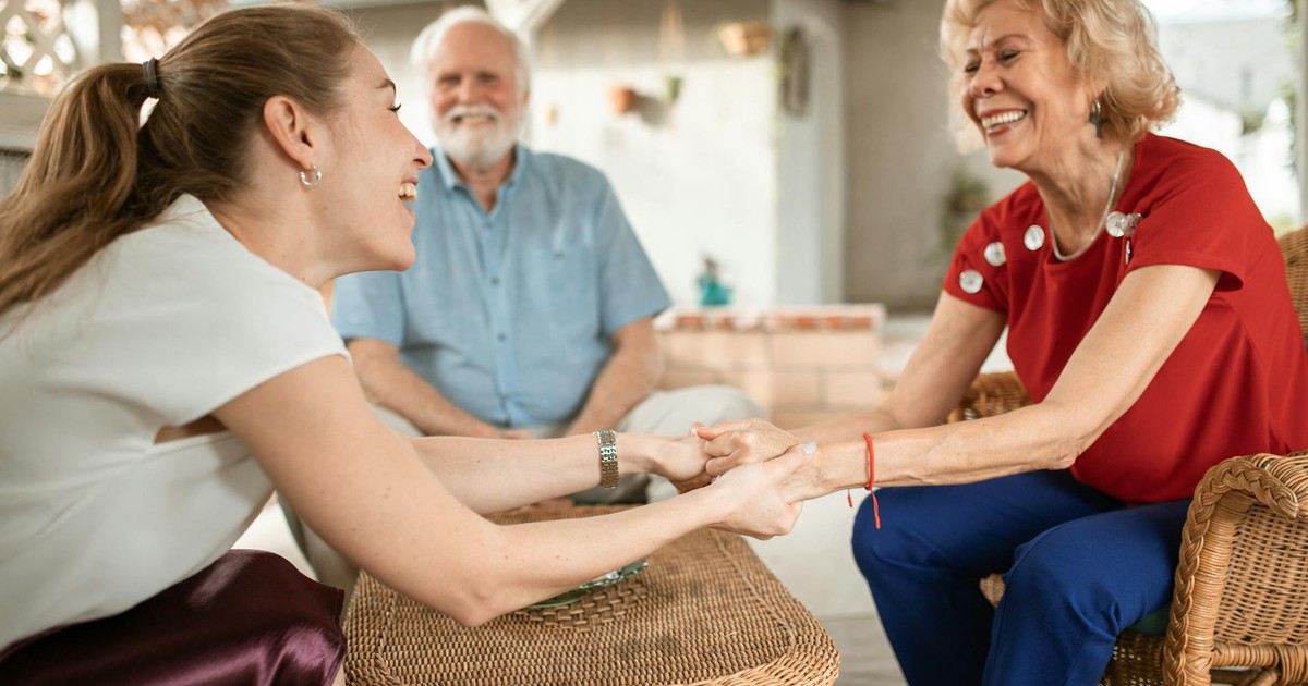 Three family members enjoying a happy conversation outside, sharing laughter and smiles.