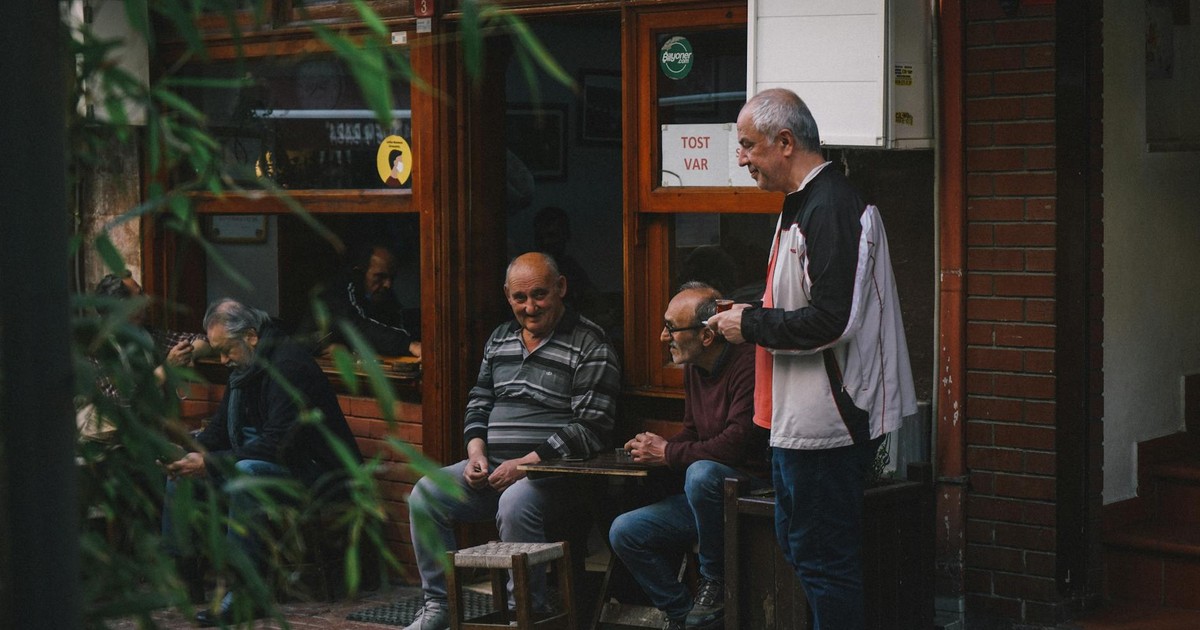 Three elderly males enjoying a conversation outside a cozy cafe.