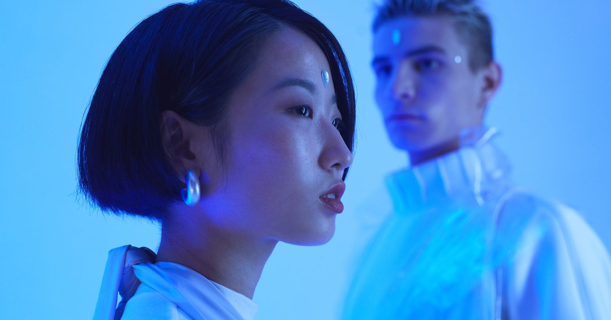 Futuristic fashion portrait of an Asian woman and Caucasian man in blue lighting.