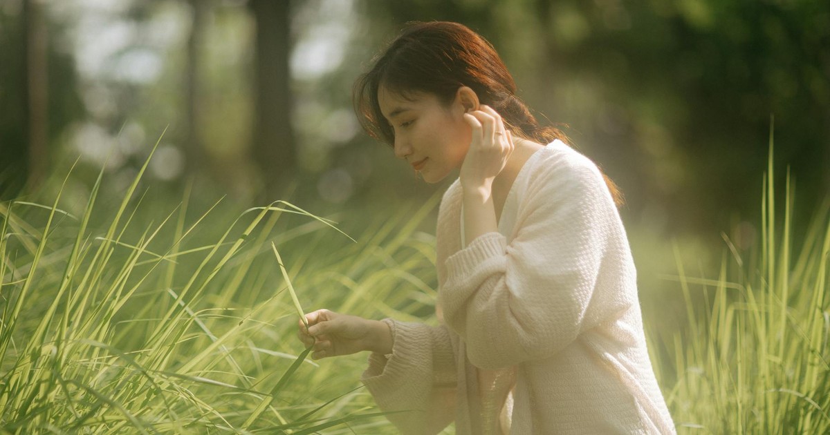 A serene moment of a young woman exploring lush greenery outdoors on a sunny day.