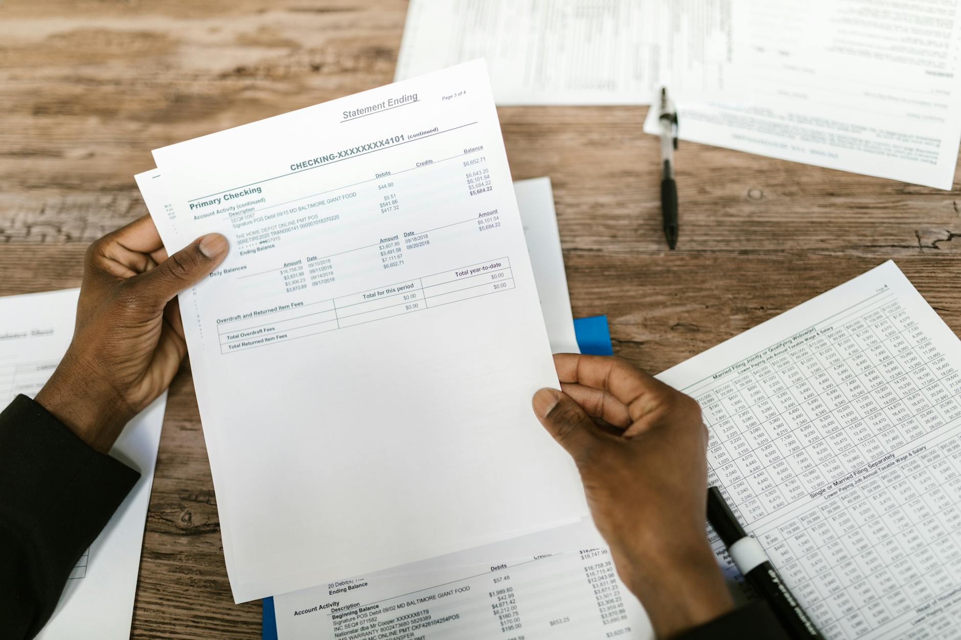Hands holding financial papers for tax preparation and analysis.