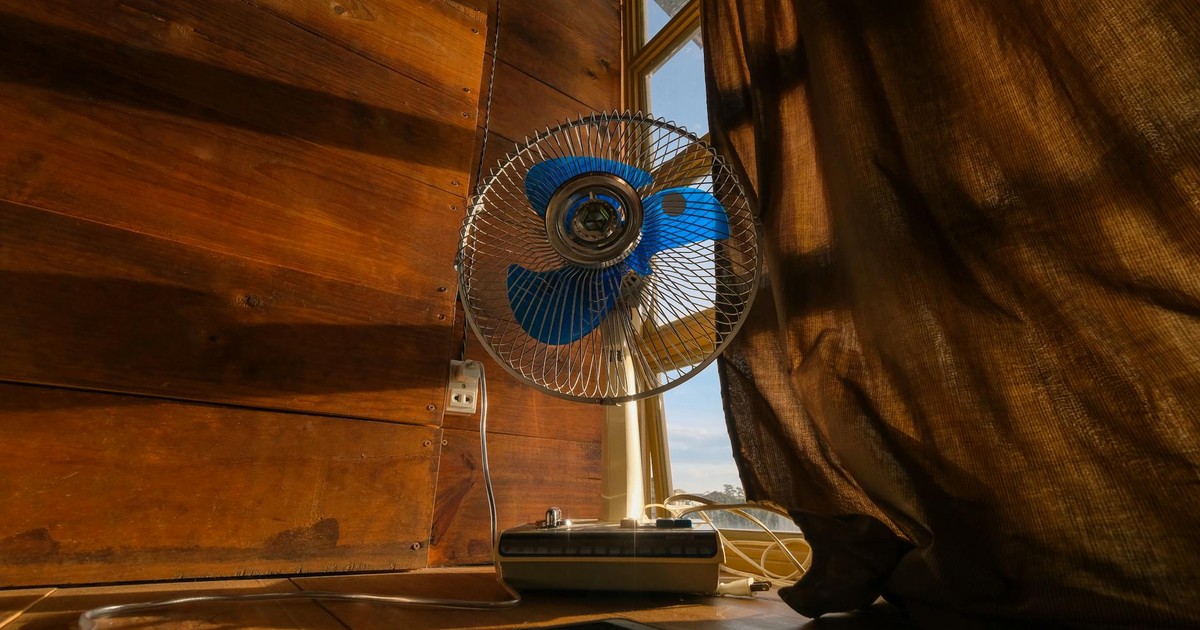 A nostalgic scene featuring an electric fan and cellphone by a sunlit curtain.
