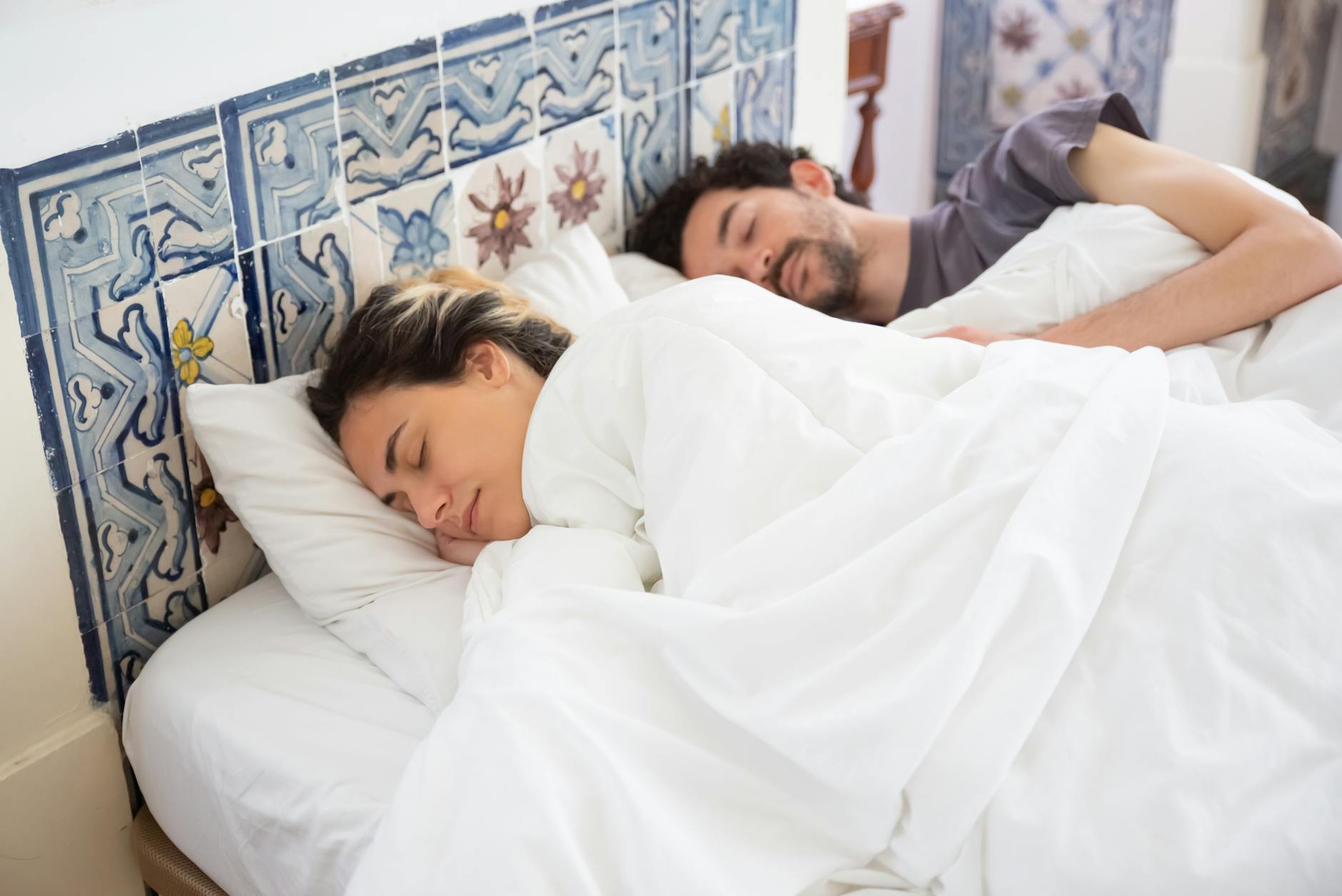 Couple sleeping peacefully in a cozy bedroom with intricate tile decor