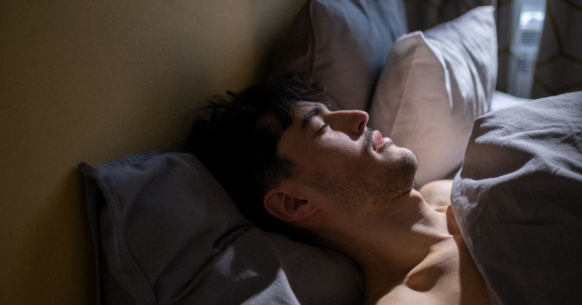 A man peacefully sleeping in bed with gentle morning light streaming in a cozy bedroom.