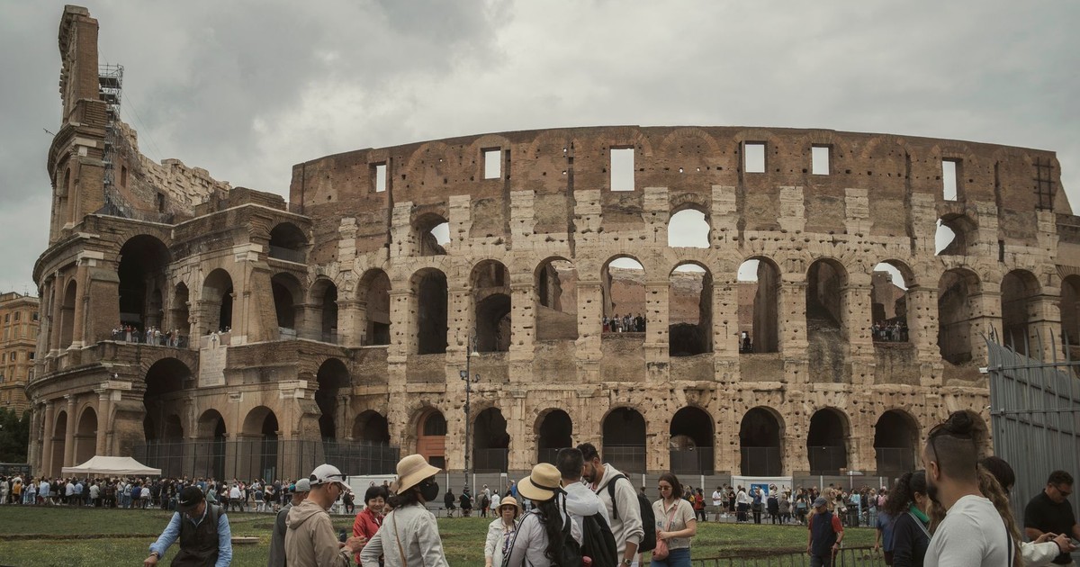Tourists gather outside the historic Colosseum in Rome, capturing its majestic ancient architecture.