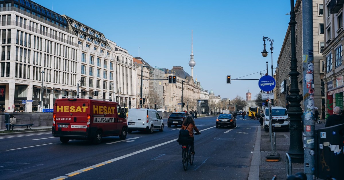 Berlin street view featuring a cyclist and iconic TV Tower under a clear blue sky.