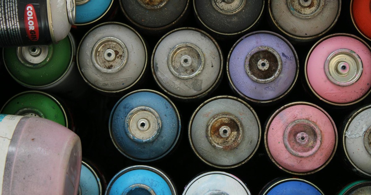 Top view of various colorful and rusty spray paint cans in storage.