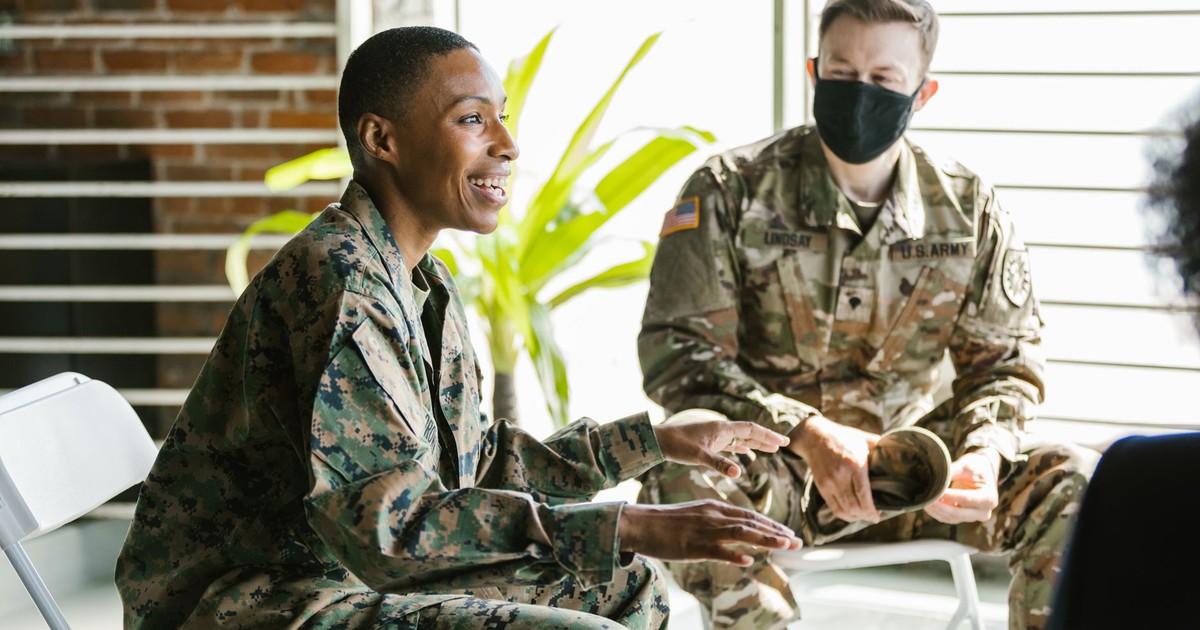 Soldiers in military uniforms discussing during a therapy session indoors.