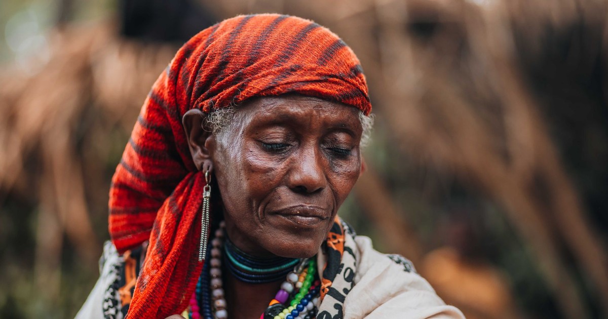 Close-up of an elderly woman wearing colorful traditional headscarf and jewelry.