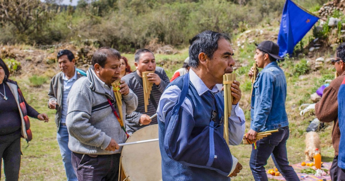 A group of musicians playing pan flutes in an outdoor traditional performance in Concepción, Peru.