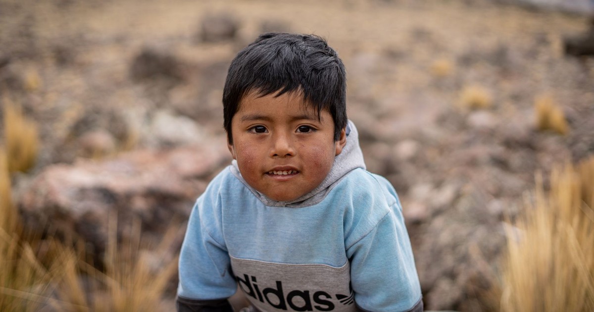 Close-up portrait of a smiling young boy in rural Peru wearing a hoodie. Captures the essence of native life.