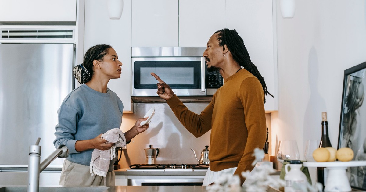 Discontented African American male menacing to female partner with finger up while looking at each other during dispute at home