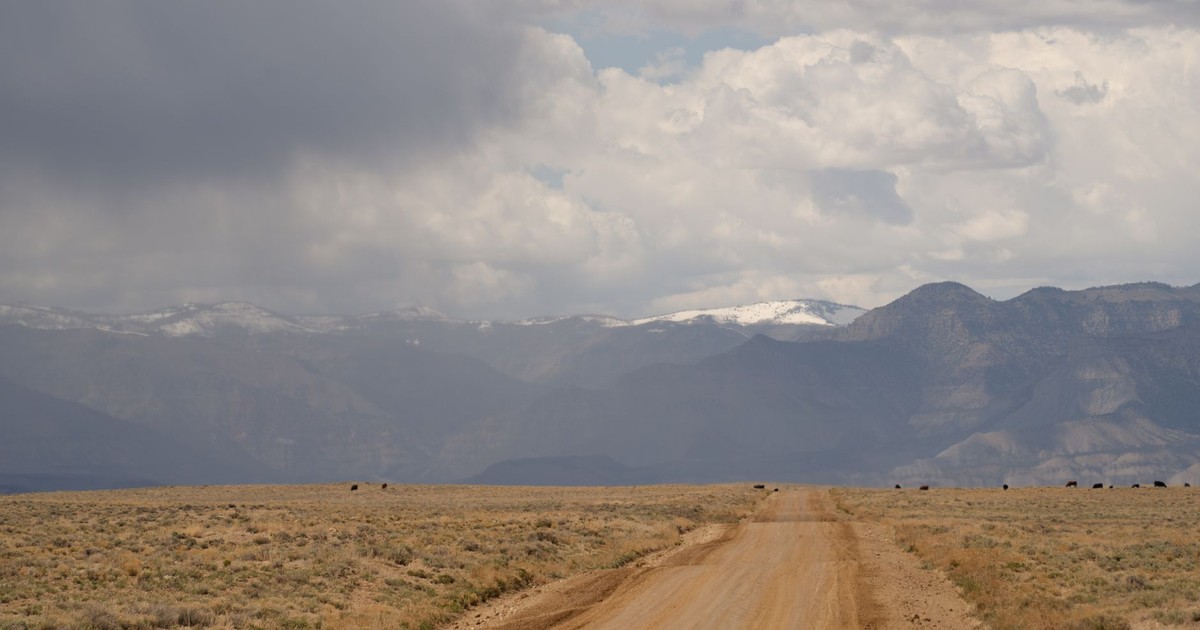 Scenic dirt road in Castle Dale, Utah, with mountains under dramatic sky.