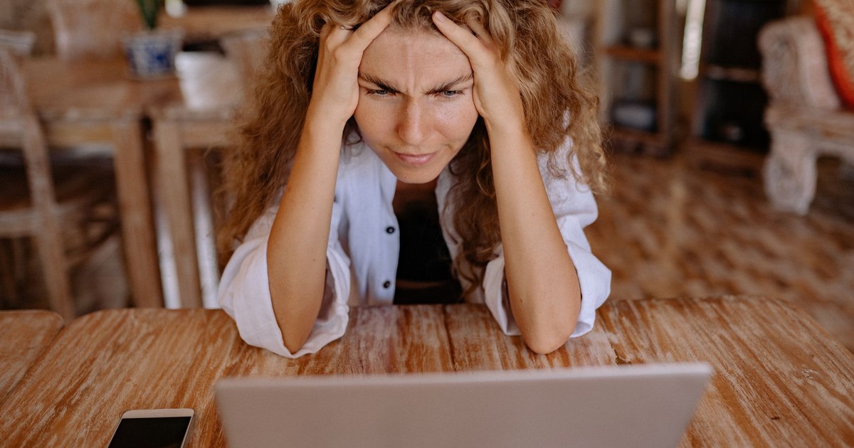 Stressed woman at home struggling with remote work on her laptop.