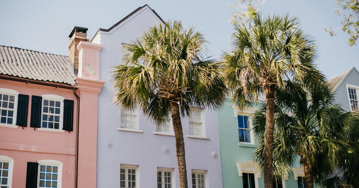 Vibrant pastel homes and palm trees on a sunny street in Charleston.