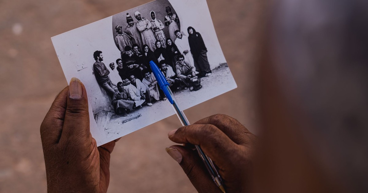 Hands holding a vintage photograph with a pen, capturing memories in Tiznit, Morocco.