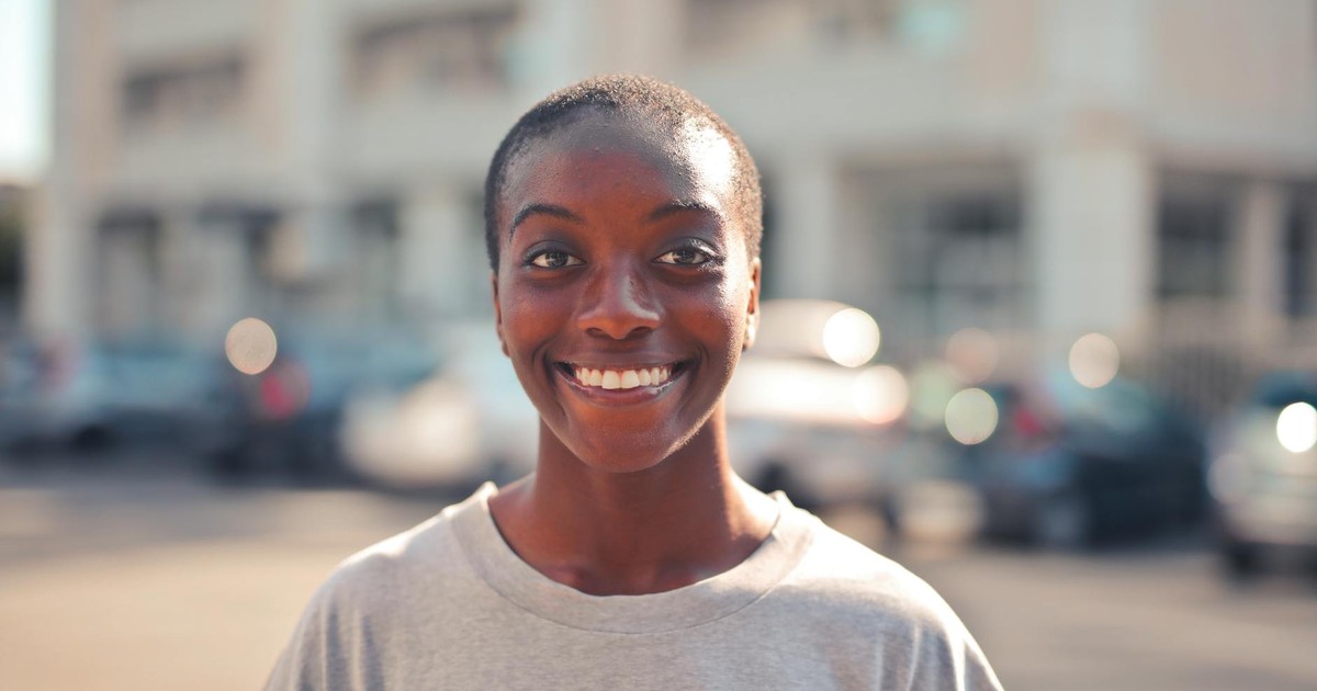 Happy woman smiling outdoors with a soft focus background.
