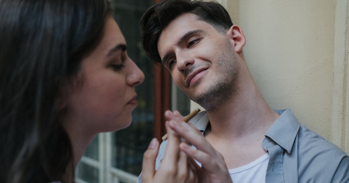 A couple enjoys a smoking break, sharing a connection outdoors in a calm setting.