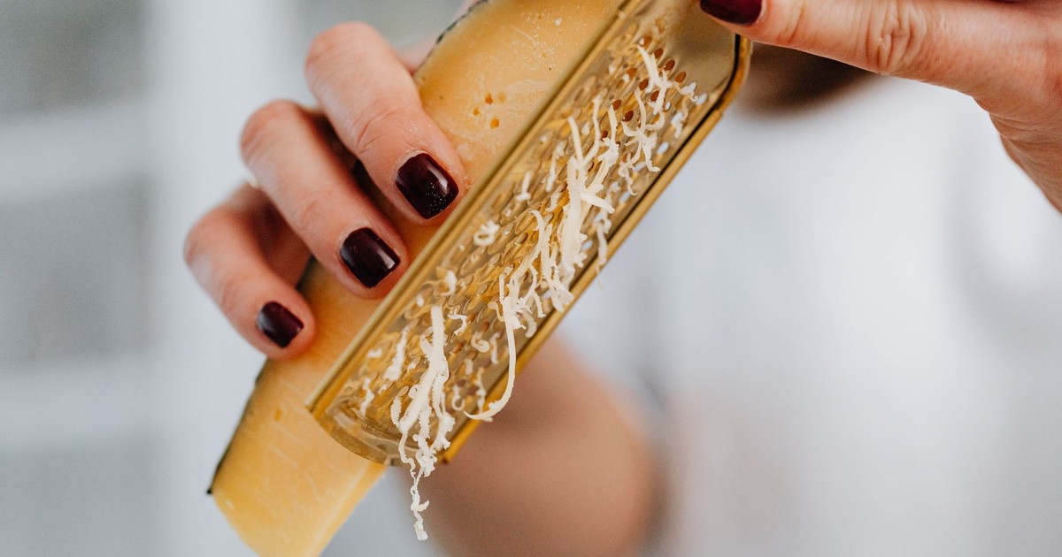 Close-up image of grated parmesan cheese with focus on hands and food preparation.