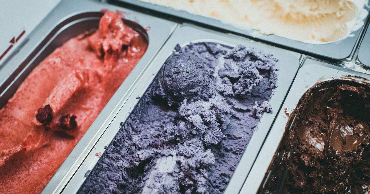 A close-up view of various flavored ice cream in metal trays, showcasing vibrant colors and textures.