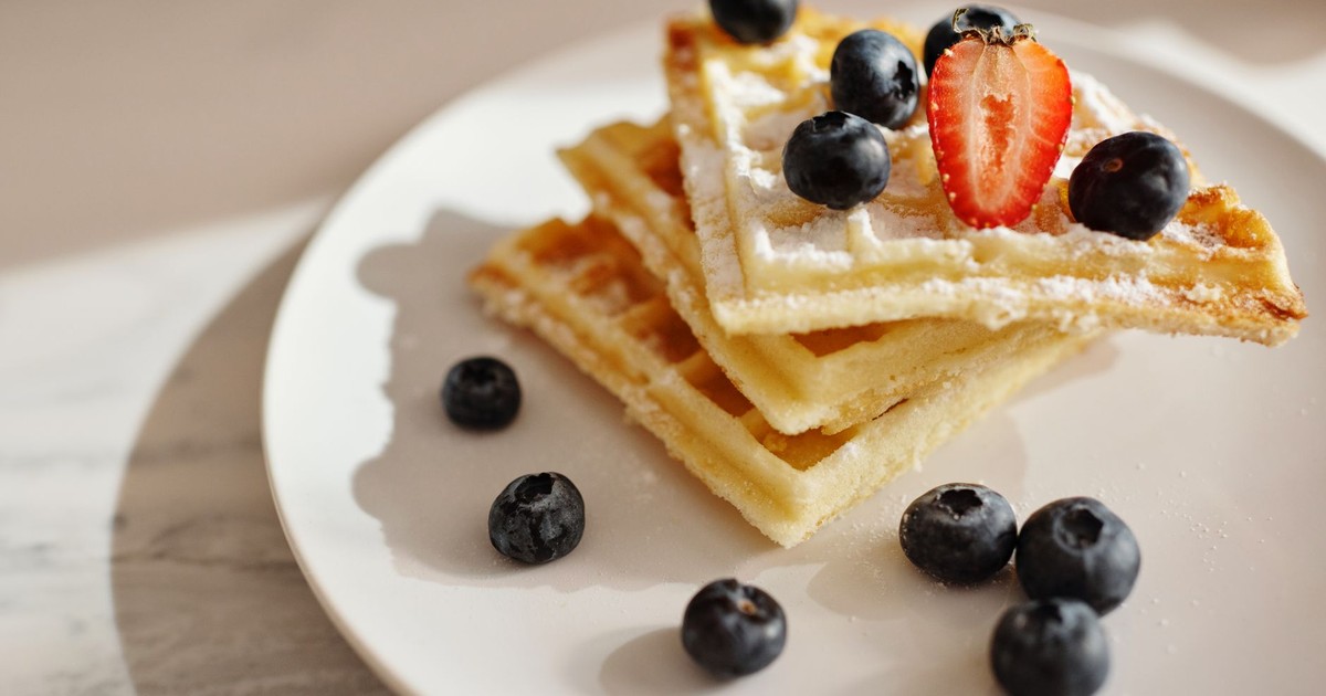 Yummy waffles topped with fresh blueberries, strawberries, and sugar powder.