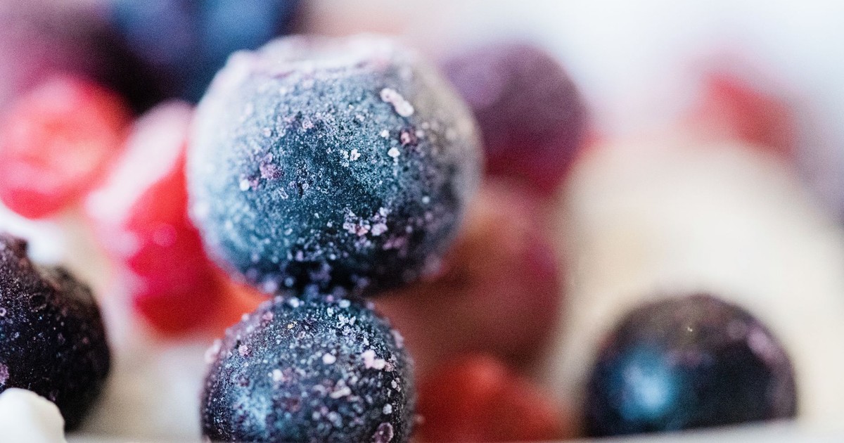 Frozen blueberries and fruits in a close-up shot, showcasing frost and vibrant colors.
