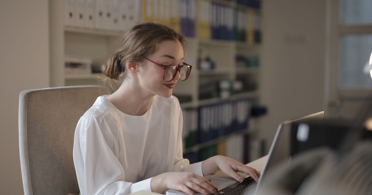 A professional woman concentrating on her laptop at a modern office desk.