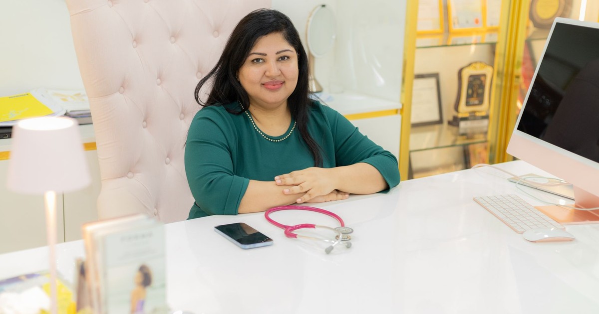 Confident woman sitting at a modern office desk with a stethoscope, portraying professionalism and healthcare.