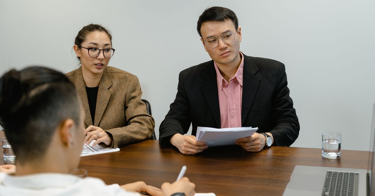 Colleagues engaged in a business meeting, discussing documents in an office setting.
