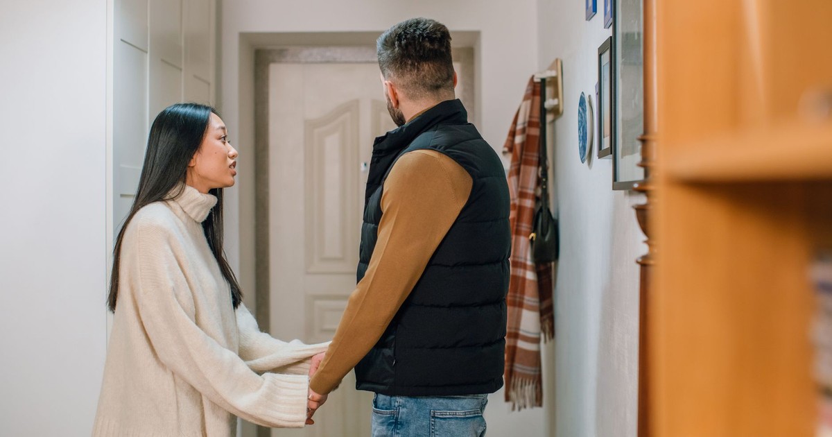 A couple engages in a serious conversation, holding hands inside a cozy home.