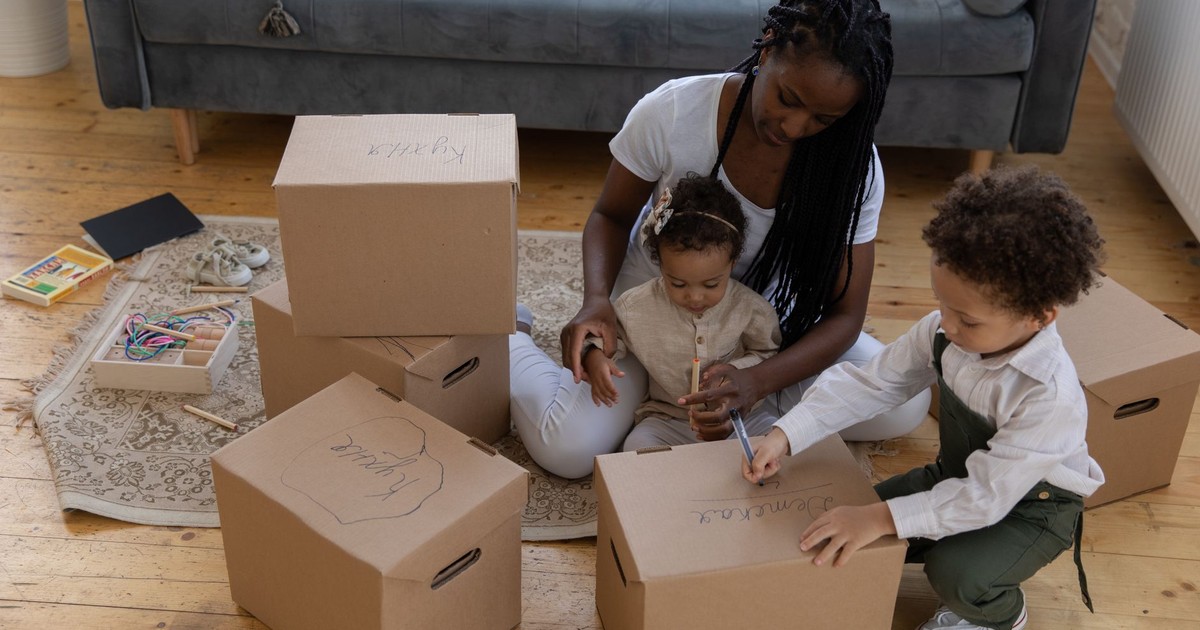 Mother and children packing boxes together in cozy living room environment.