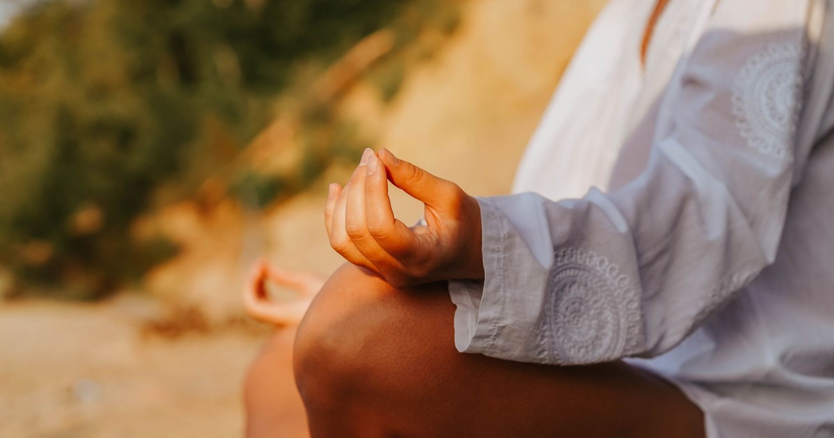 A close-up of a person meditating outdoors, capturing mindfulness at sunset on a beach.