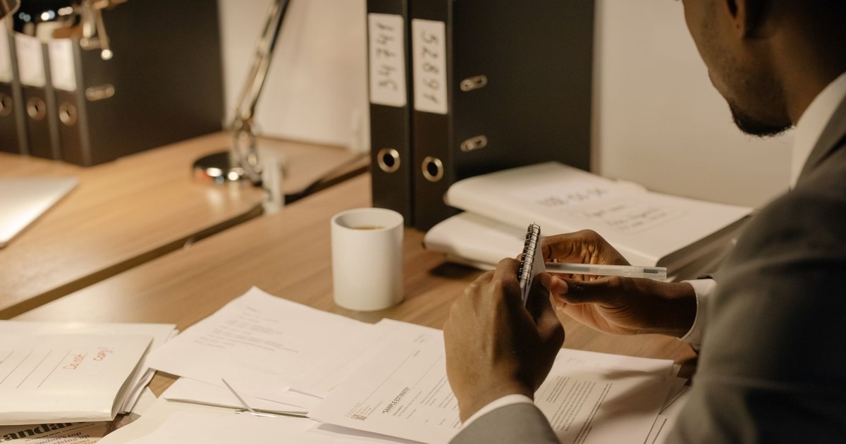Man in gray suit reviewing documents at an organized workspace.