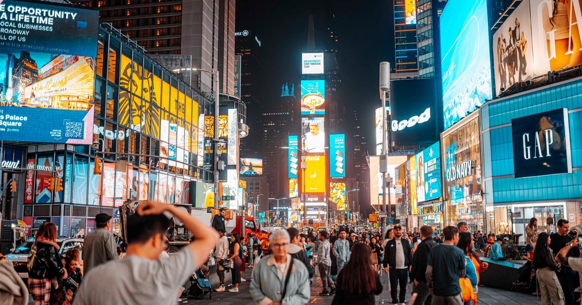 Capture of bustling Times Square at night, showcasing iconic billboards and a lively crowd.