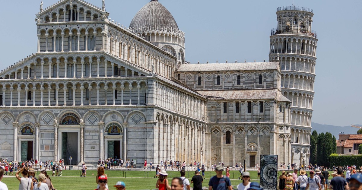 Crowds explore the Pisa Cathedral and iconic Leaning Tower on a sunny day in Pisa, Italy.