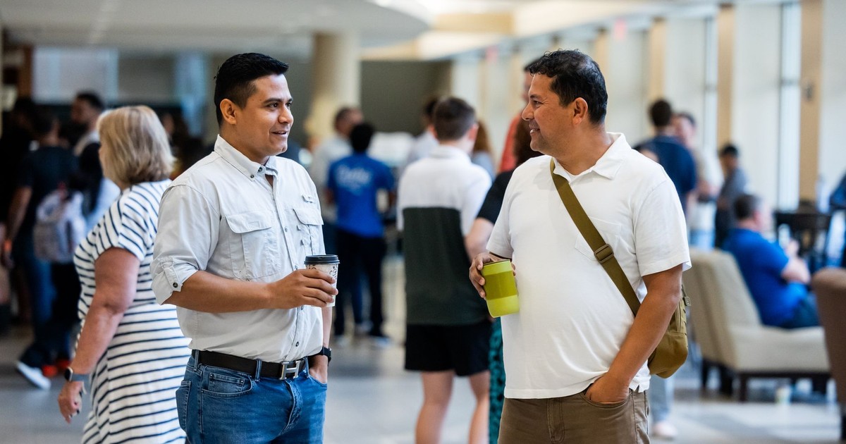 Two adults engaging in casual conversation during an indoor networking event.